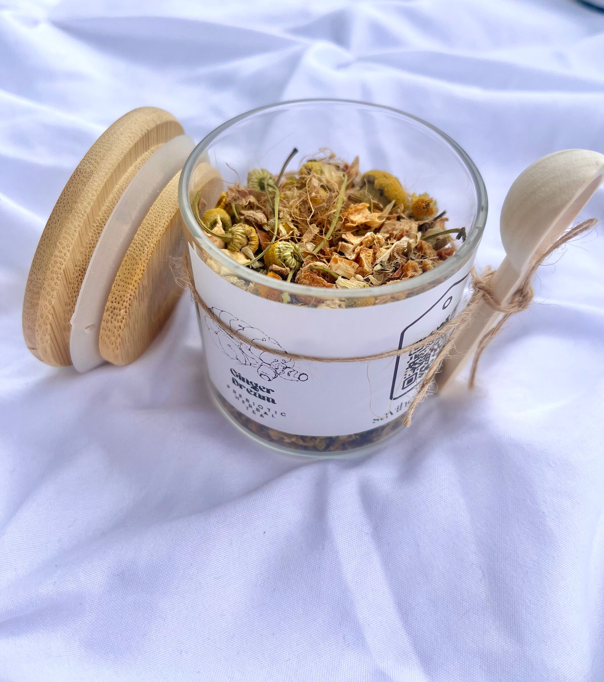 Glass jar with dried herbs on a white fabric background