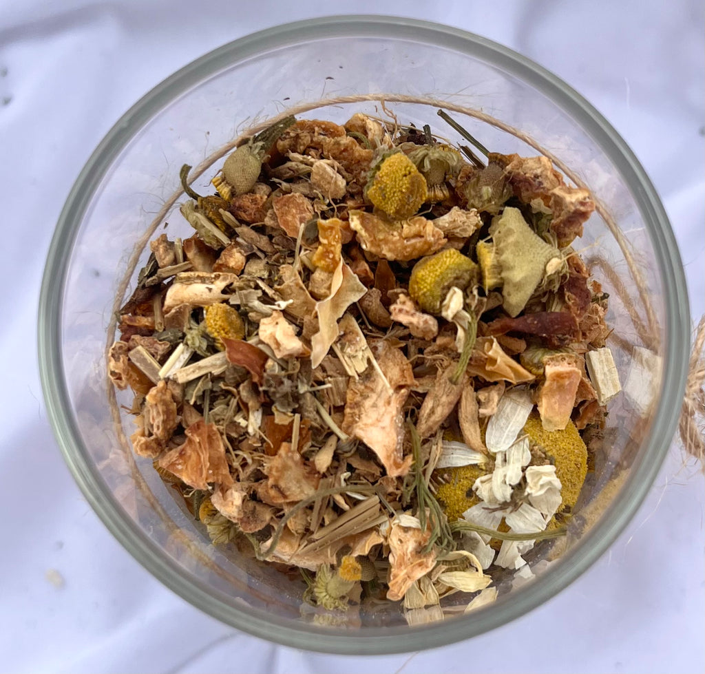 Glass bowl filled with a mix of dried herbs and flowers on a white background
